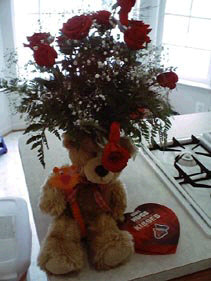 Long-stemmed red roses, a cinnamon-colored teddy bear and a heart-shaped box of chocolates.